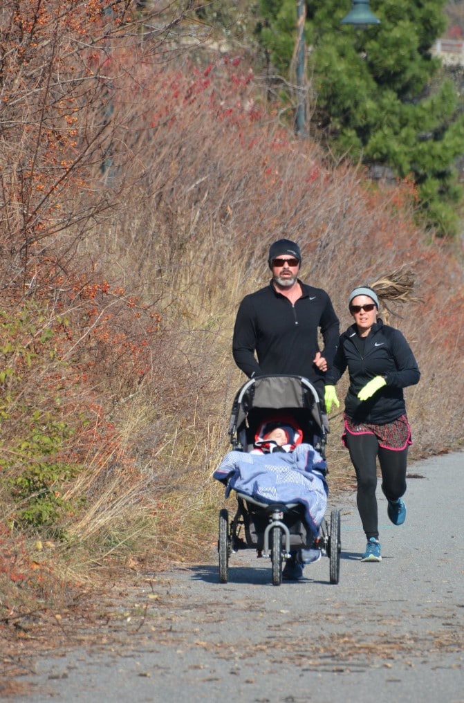 man and woman running with baby in stroller