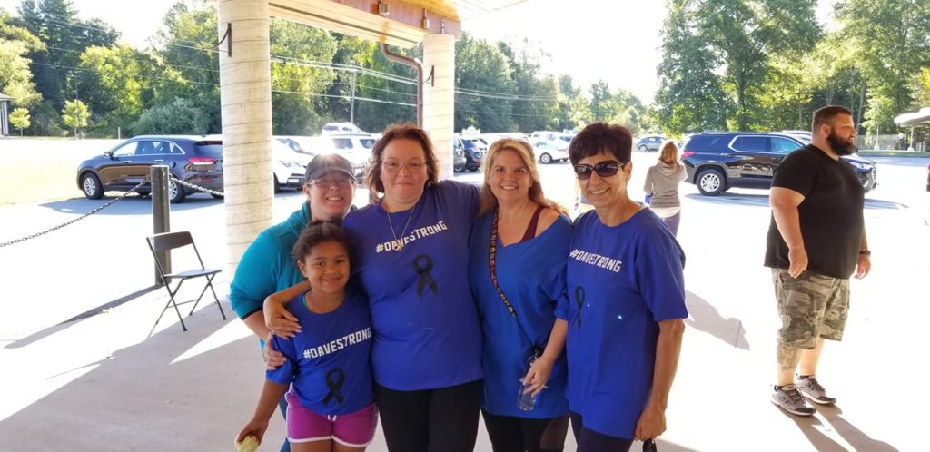 five people in blue shirts smiling